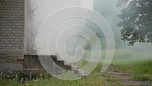 Close-up white brick house with porch from which comes puff of white smoke, danger of fires in houses and gas explosion