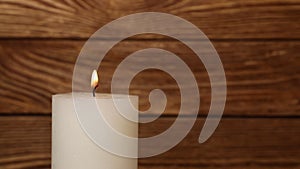 Close up white candle trembling flame over wood