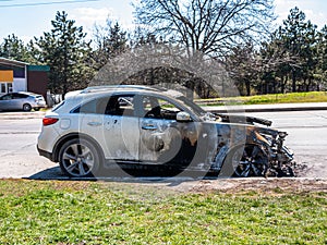 Close-up of a white car on a burnt-out car on the side of the road