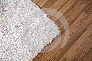 Close-up white carpet on laminate wood floor in living room, interior decoration