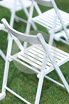 Close up white chairs on grass.