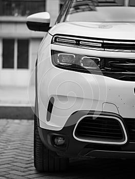 A close-up of a white Citroen C5 aircross SUV`s right HELLA LED headlights and turn signal windows