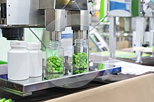 Close up white with clear plastic bottle under nozzle dispenser component of automatic medicine capsule bottle filling and