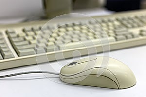 Close-up of white computer mouse on blurred PC keyboard background. Modern technology, information and communication concept