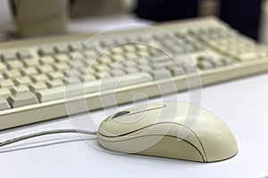 Close-up of white computer mouse on blurred PC keyboard background. Modern technology, information and communication concept