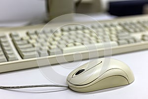 Close-up of white computer mouse on blurred PC keyboard background. Modern technology, information and communication concept