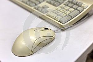 Close-up of white computer mouse on blurred PC keyboard background. Modern technology, information and communication concept