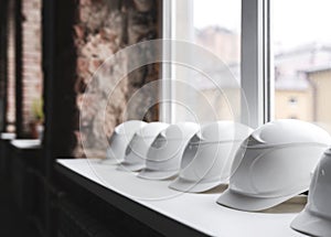 Close-up on the white construction helmets lie on the windowsill in a row inside the building under construction.