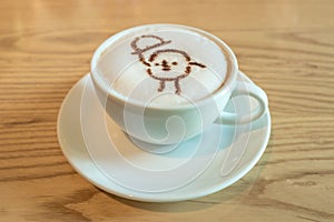 Close up a white cup of coffee with cartoon latte art made from cocoa powder