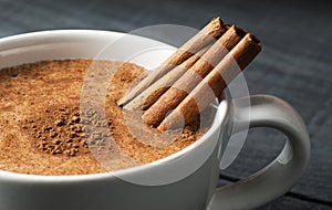 Close up white cup of salep milky hot drink of Turkey with cinnamon powder