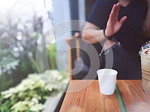 Close up white cup on the table with young woman sitting talking and drinking coffee on background