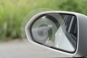 Close-up white frame of mirror wing of car. With asphalt road reflection from glass.