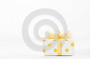 Close up of white gif box with golden star pattern and gold ribbon bow on bokeh background photo