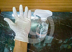 Close-up, white gloved hand and alcohol spray, black marble table background.