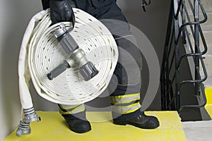 Close-up of a white hose and a water supply barrel, in the hands of a firefighter, against the background of the stairs of a