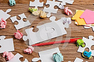 Close-Up White Jigsaw Pattern Puzzle Pieces To Be Connected With Missing Last Piece Positioned On A Flat Lay Background