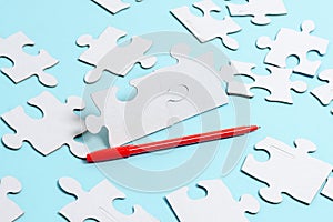 Close-Up White Jigsaw Pattern Puzzle Pieces To Be Connected With Missing Last Piece Positioned On A Flat Lay Background With