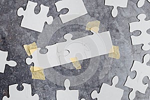 Close-Up White Jigsaw Pattern Puzzle Pieces To Be Connected With Missing Last Piece Positioned On A Flat Lay Background With