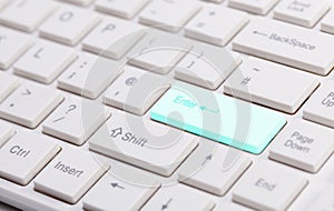 Close up of white keyboard with glowing blue enter button