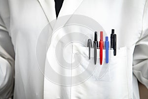 Close up of white lab coat with munticolored pens in the pocket