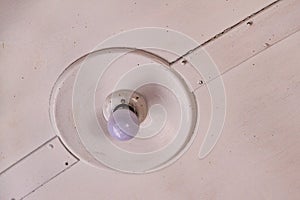 Close-up of a white lamp on a wooden ceiling