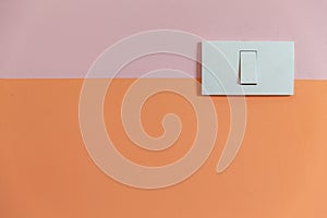 Close up of white Light Switch with copy space on pink and orange wall.