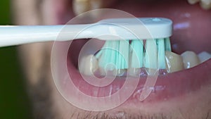 Close up of white man brushing his teeth with an electric toothbrush. Man`s open mouth as he brushes his teeth.