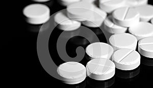 Close up of white painkiller tablet on a reflective black backgr