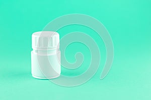 Close up white pill bottle on aquamarine background with copy space. Focus on foreground, soft bokeh. Pharmacy drugstore concept