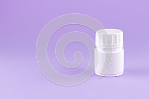 Close up white pill bottle on purple background with copy space. Focus on foreground, soft bokeh. Pharmacy drugstore concept