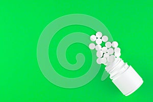Close up white pill bottle with spilled out pills on lime green background with copy space. Focus on foreground, soft bokeh. Pharm