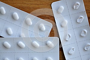 Close-up of White pills in blister packets on a wooden surface