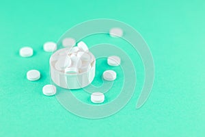 Close up white pills and capsules in cap on aquamarine background with copy space. Focus on foreground, soft bokeh. Pharmacy drugs