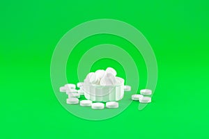 Close up white pills and capsules in cap on lime green background with copy space. Focus on foreground, soft bokeh. Pharmacy drugs