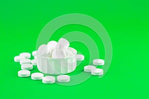 Close up white pills and capsules in cap on lime green background with copy space. Focus on foreground, soft bokeh. Pharmacy drugs