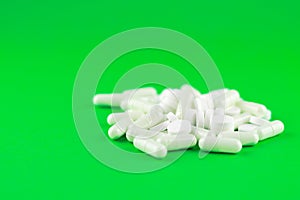 Close up white pills and capsules on lime green background with copy space. Focus on foreground, soft bokeh. Pharmacy drugstore co