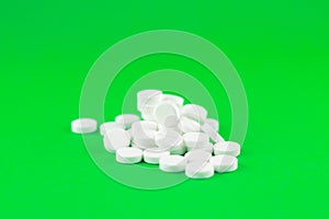 Close up white pills on lime green background with copy space. Focus on foreground, soft bokeh. Pharmacy drugstore concept