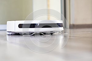 close-up of a white robot vacuum cleaner automatically cleaning the white wool of the house. horizontal