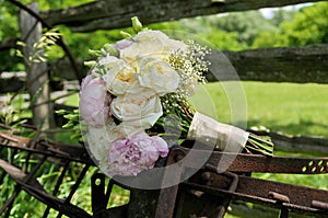 Close up of White Rose and Pink Peonies Wedding Bouquet on Rusty Farm Equipment