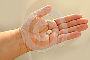 close up white shell pill, drugs on female hand on white background, research, concept taking painkillers, maintaining health,