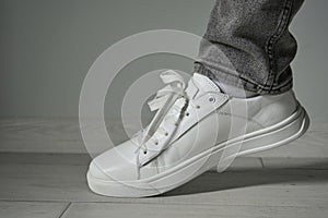 close-up of white sneakers on the leg, fashionable style of shoes, sneakers with jeans on a boy