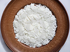 Close up of white soy wax flakes on brown plate