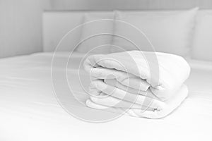 Close-up: The white towels are neatly folded and placed on the white bed. Hotel