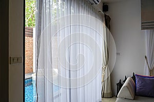 Close up white transparent curtain in hotel villa with pool background