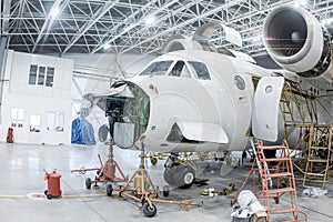 Close-up of white transport aircraft in the hangar. Airplane under maintenance