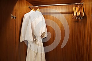 Close up white two bathrobes in wooden wardrobe for shower in luxury hotel bedroom