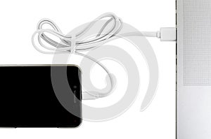 Close-up white usb cable connect phone and laptop computer new technology concept