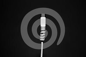 Close-up of white USB type-c charge connector with cable protection on black background.
