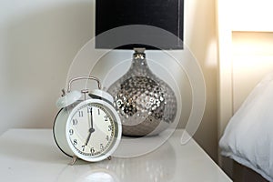 Close up the white vintage clock in the bedroom, the clock showing 7 o`clock  7 am  in the monring.