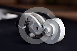 Close up of a white violin scroll with black pegbox on blurry background photo